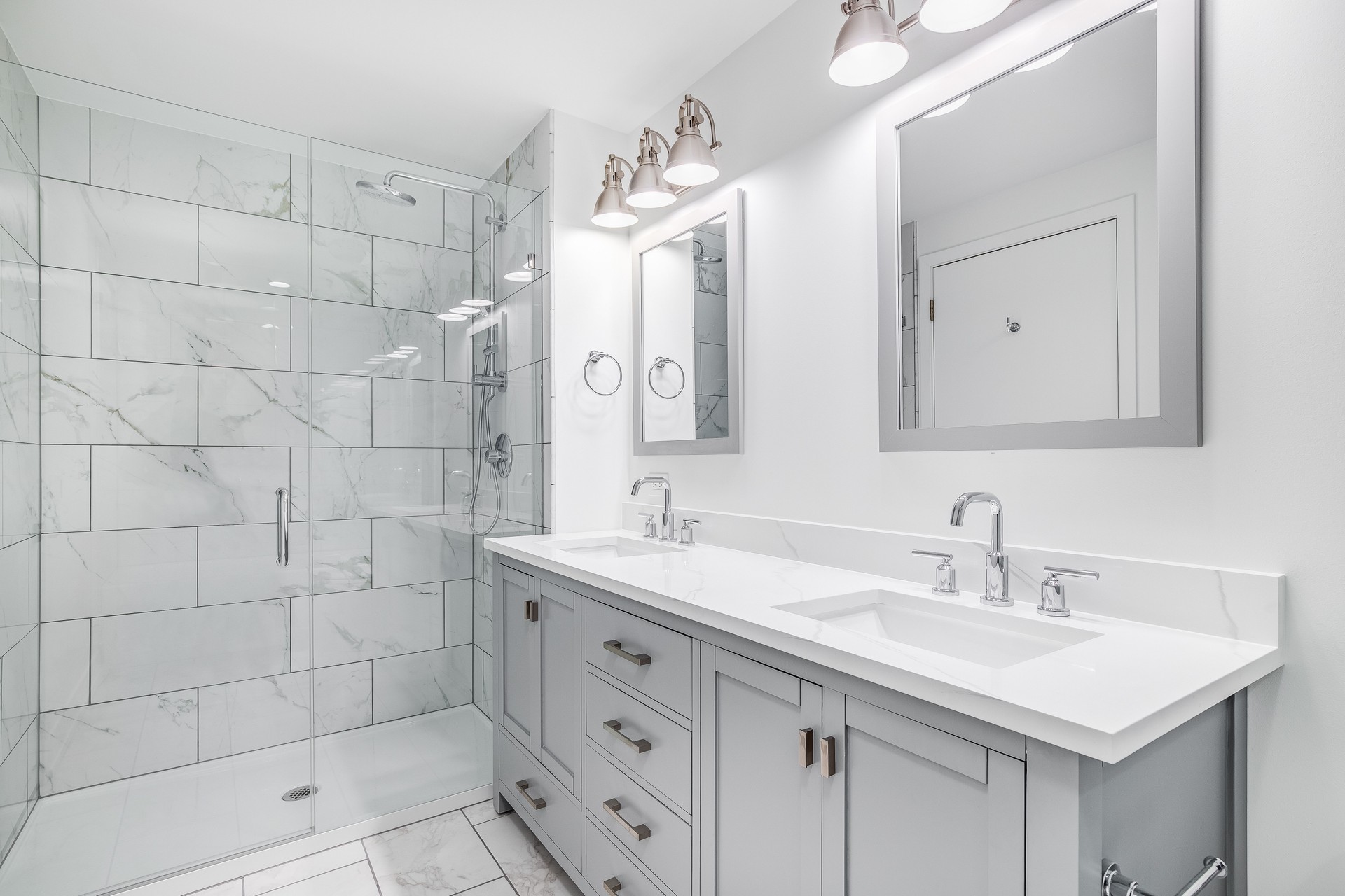 A bathroom with a grey cabinet and tiled shower.